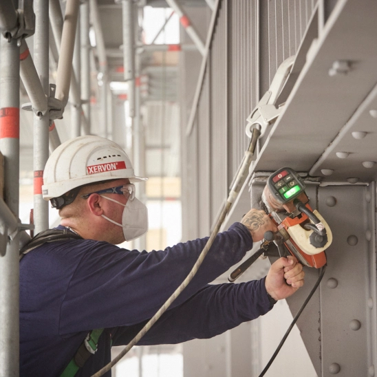 Worker in protective equipment grinding a beam