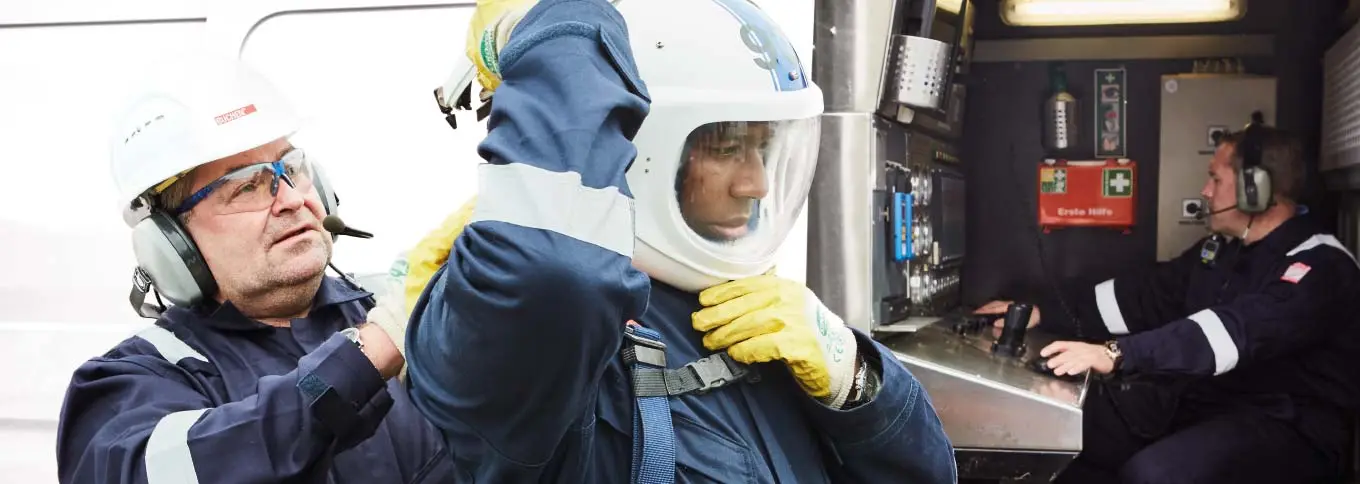 Employee in work clothes checks the fit of his colleague's helmet